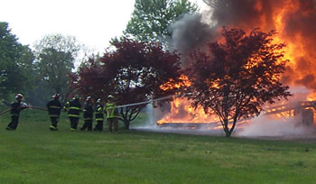 Firefighters practice putting out a house fire as part of a controlled burn