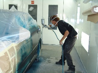 A worker sprays paint onto a car body