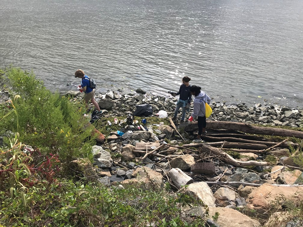 A group of volunteers collects trash along the Delaware River
